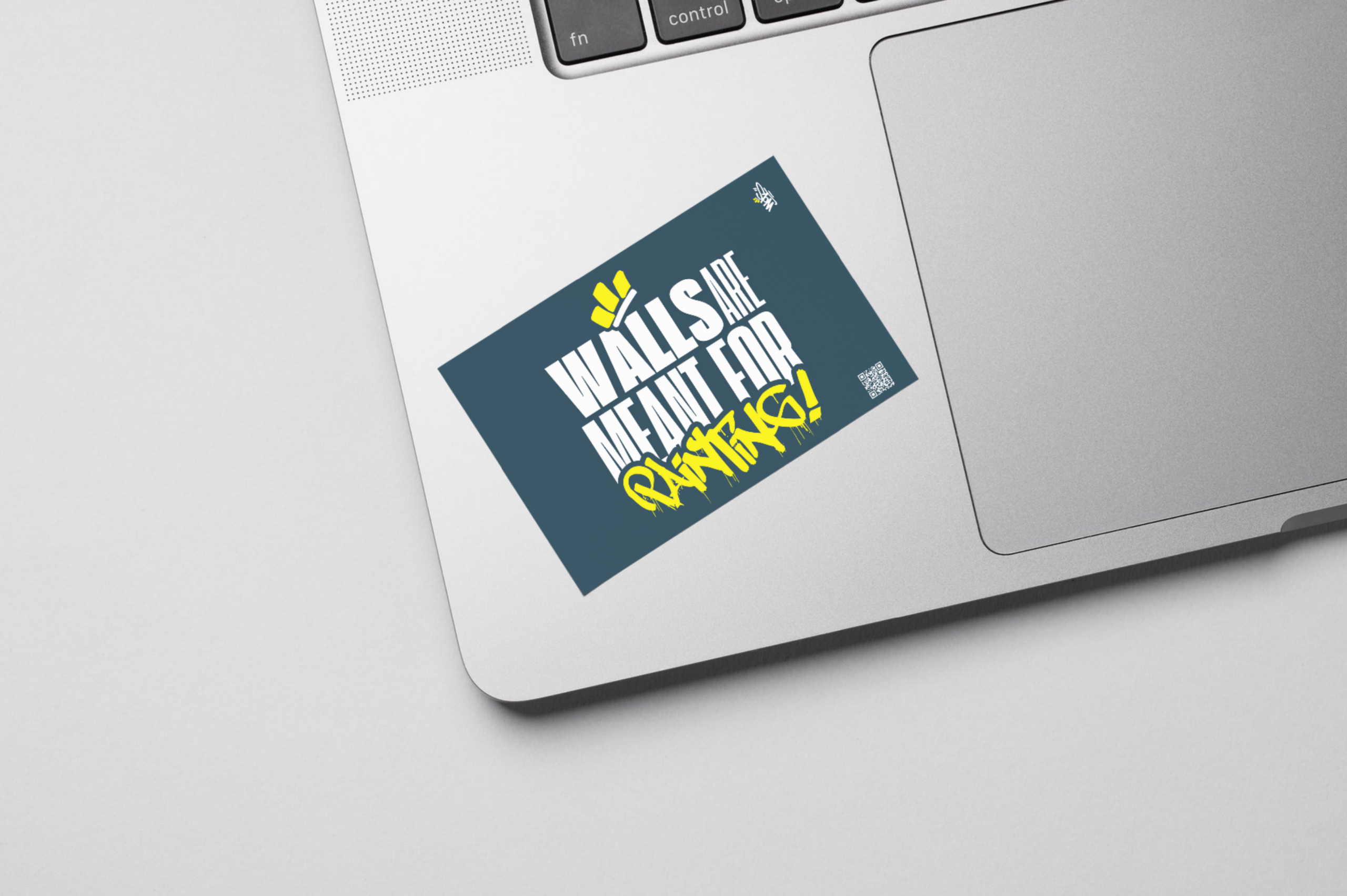 Sticker bleu WOLS avec slogan "Walls are meant for painting" collé sur PC portable.