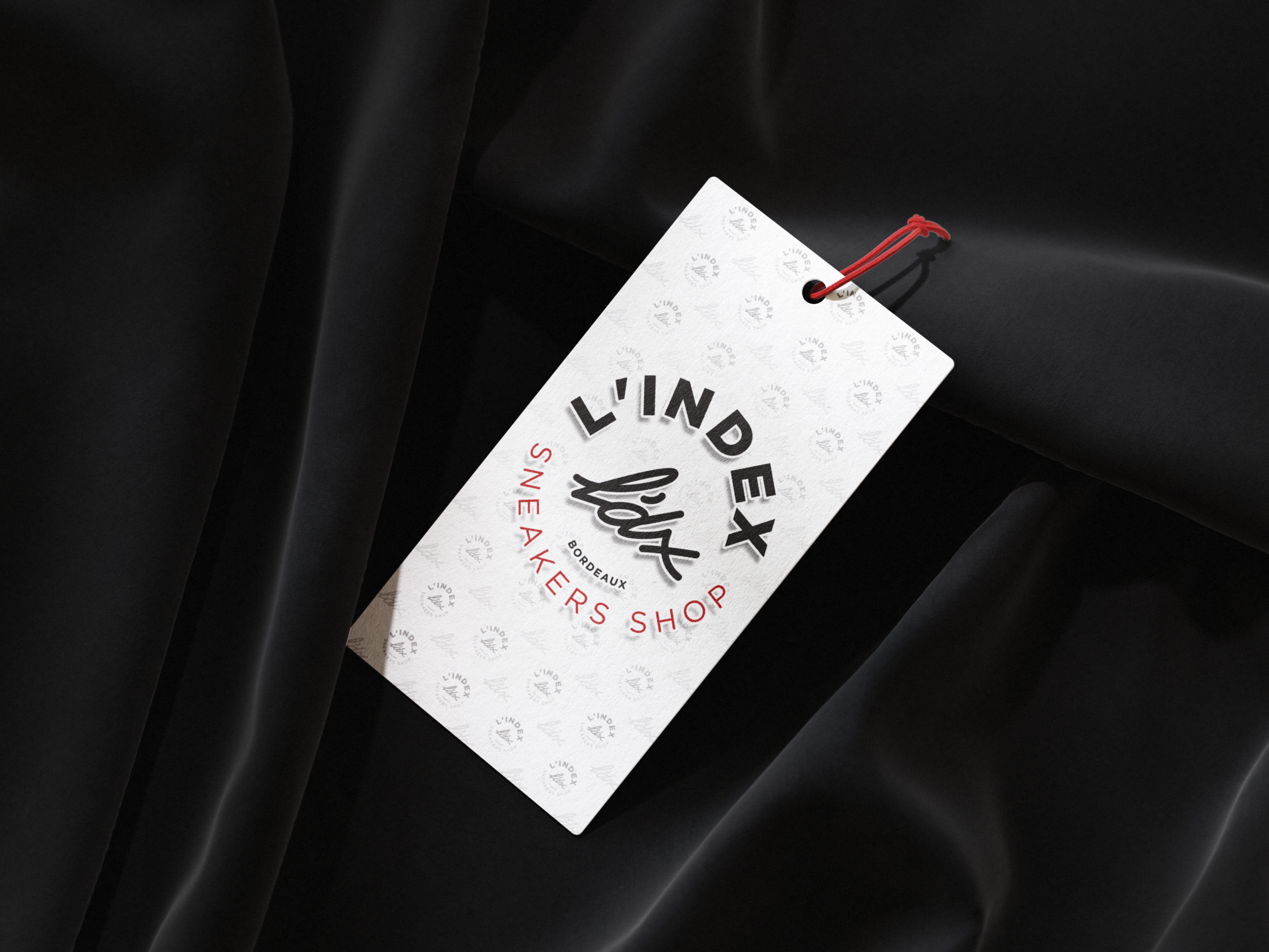 Recto d'une étiquette de suspension blanche L'INDEX SHOP.